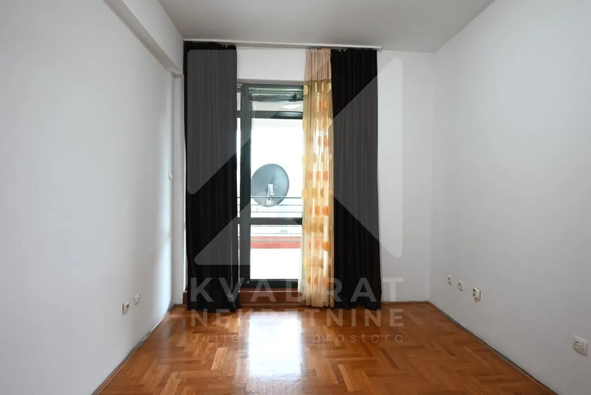 Empty room with parquet flooring and balcony doors with curtains.