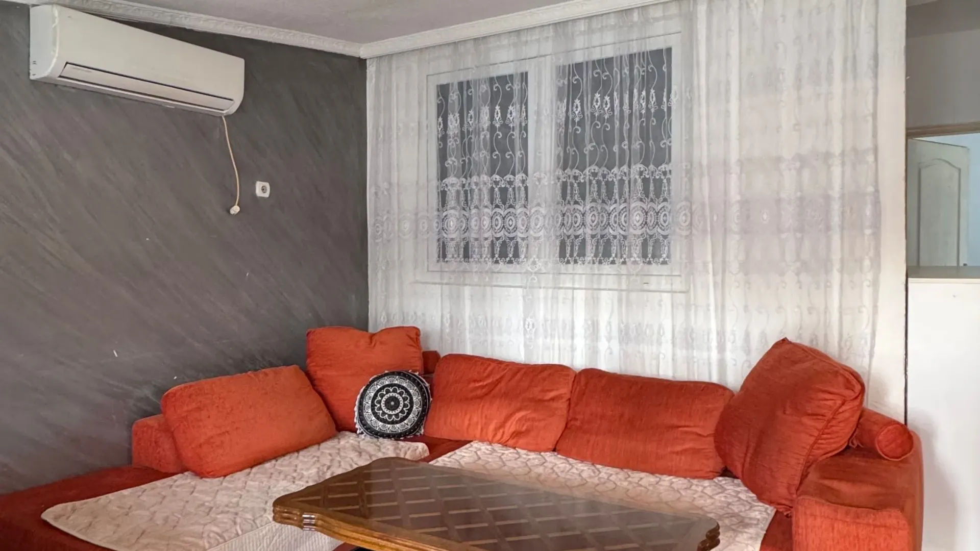 Living room with a sectional sofa, coffee table, and air conditioning unit.