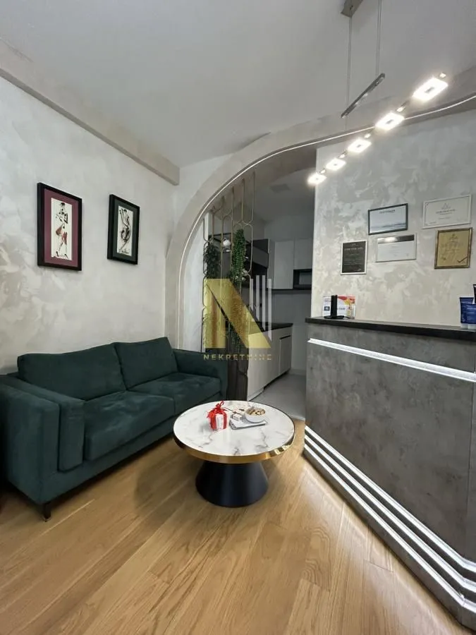 Small living room with a green sofa, a round coffee table, and a reception desk in the background.