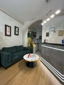 Small living room with a green sofa, a round coffee table, and a reception desk in the background. - image 2