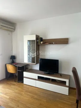 Living room with a TV unit, desk, and air conditioning. - image 2