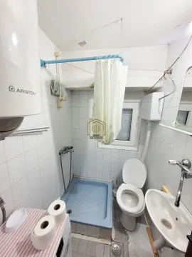 Manje kupatilo obloženo bijelim pločicama sa tuš kadom, wc šoljom i umivaonikom. - image 10