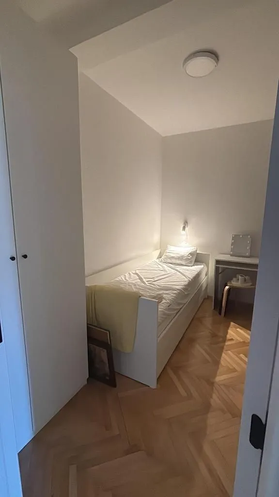 Manja spavaća soba sa krevetom i radnim stolom.
