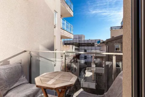 Small furnished balcony with a wooden table and a view of surrounding buildings. - image 18