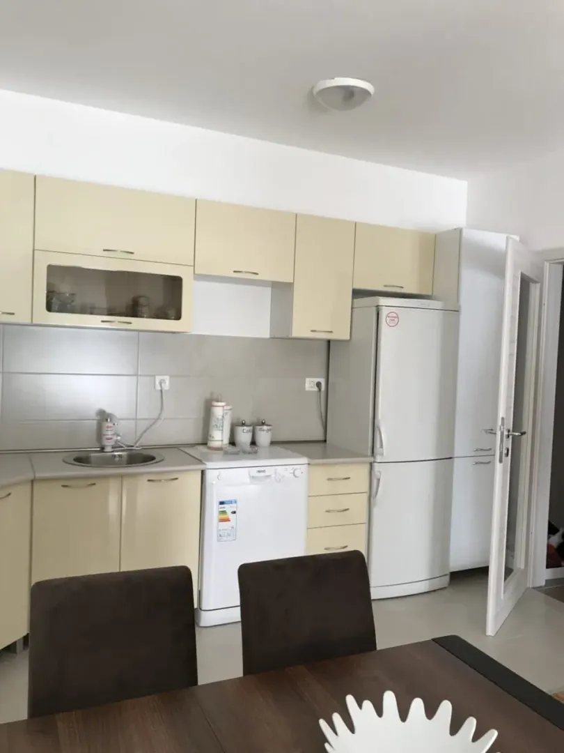 Kitchen with beige cabinets and a dining table in the foreground.