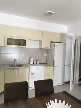 Kitchen with beige cabinets and a dining table in the foreground. - image 7