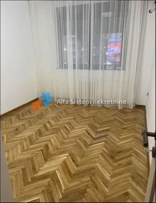 Empty room with parquet flooring and a window with curtains.