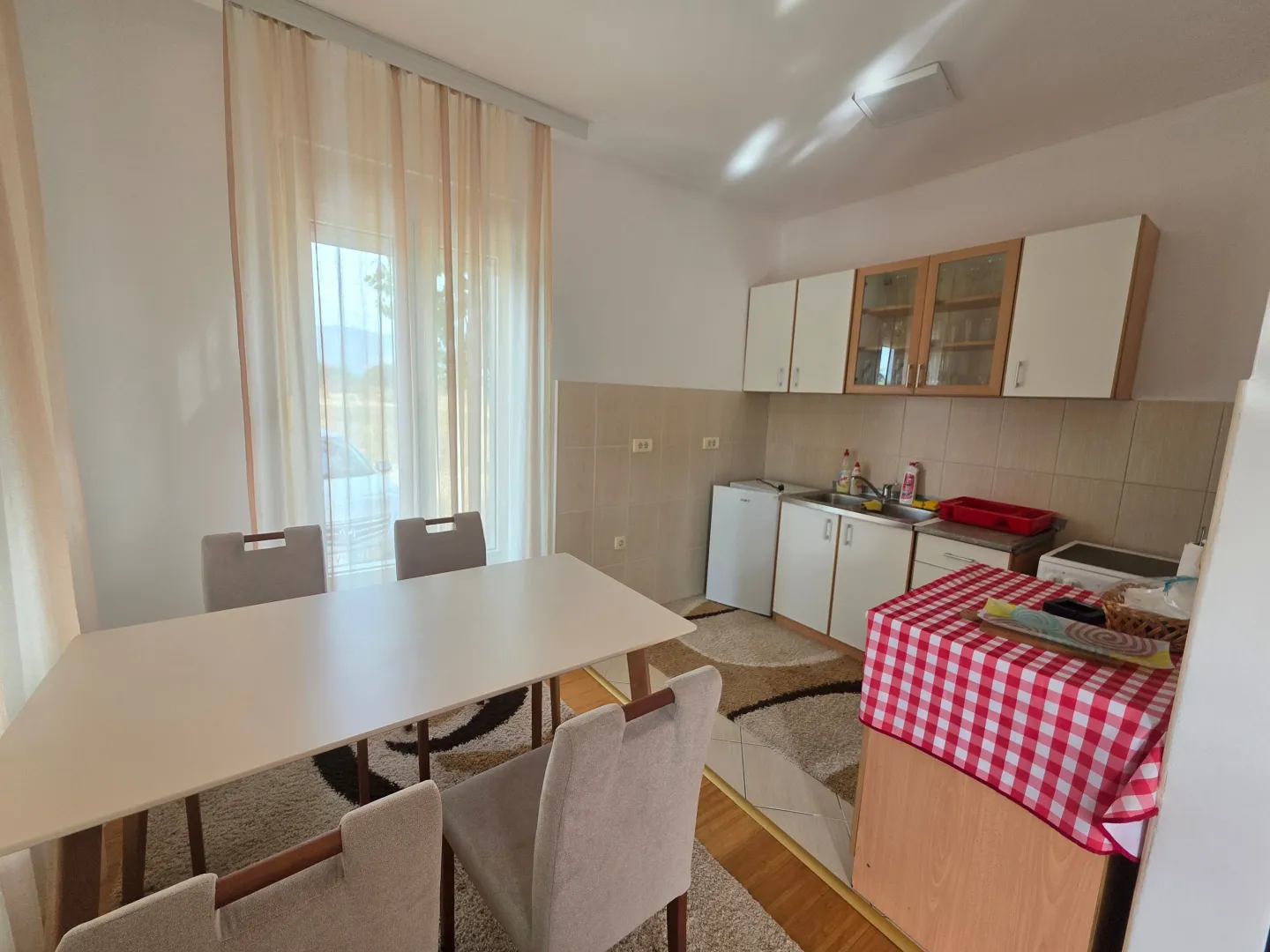 Dining area with a table and chairs and a kitchen in the background.