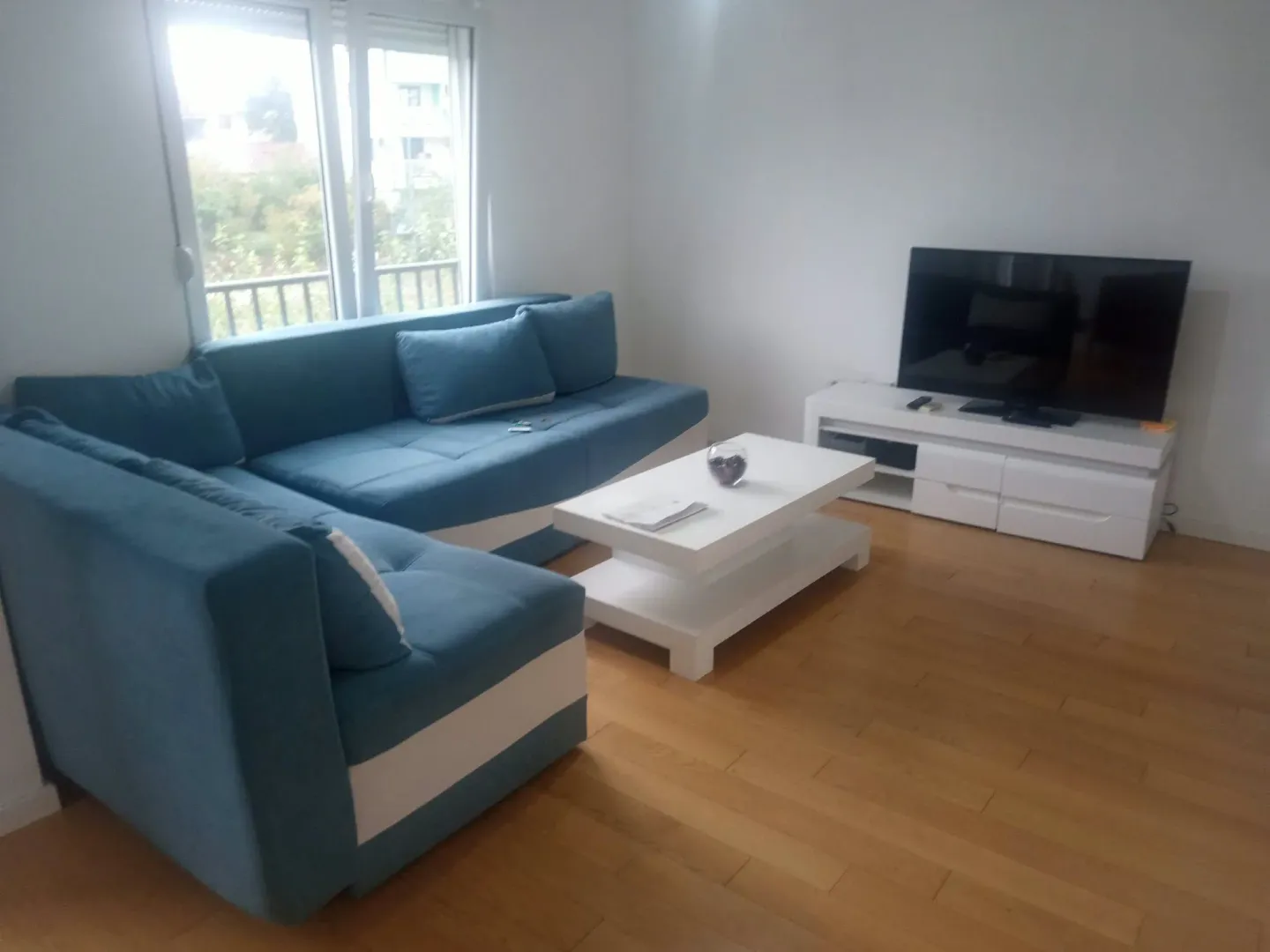Living room with a blue sectional sofa, a white coffee table, and a TV.