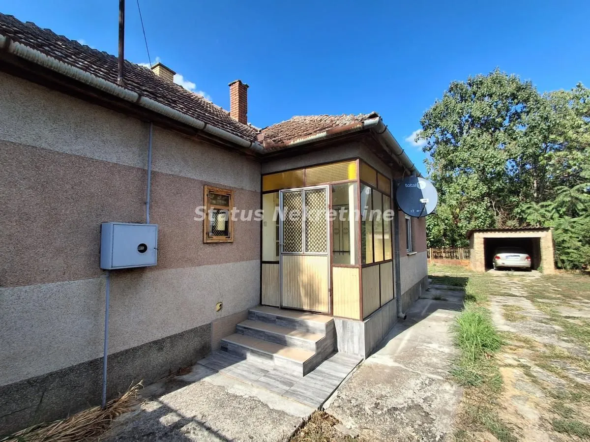 Pogled na spoljašnjost kuće sa natkrivenim ulazom i dvorištem.
