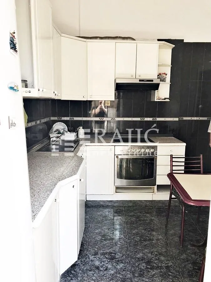 Smaller kitchen with white cabinetry and dark tiles.