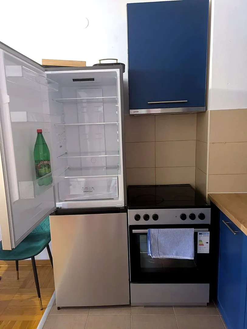 Kitchen with an open refrigerator, stove, and blue cabinets.