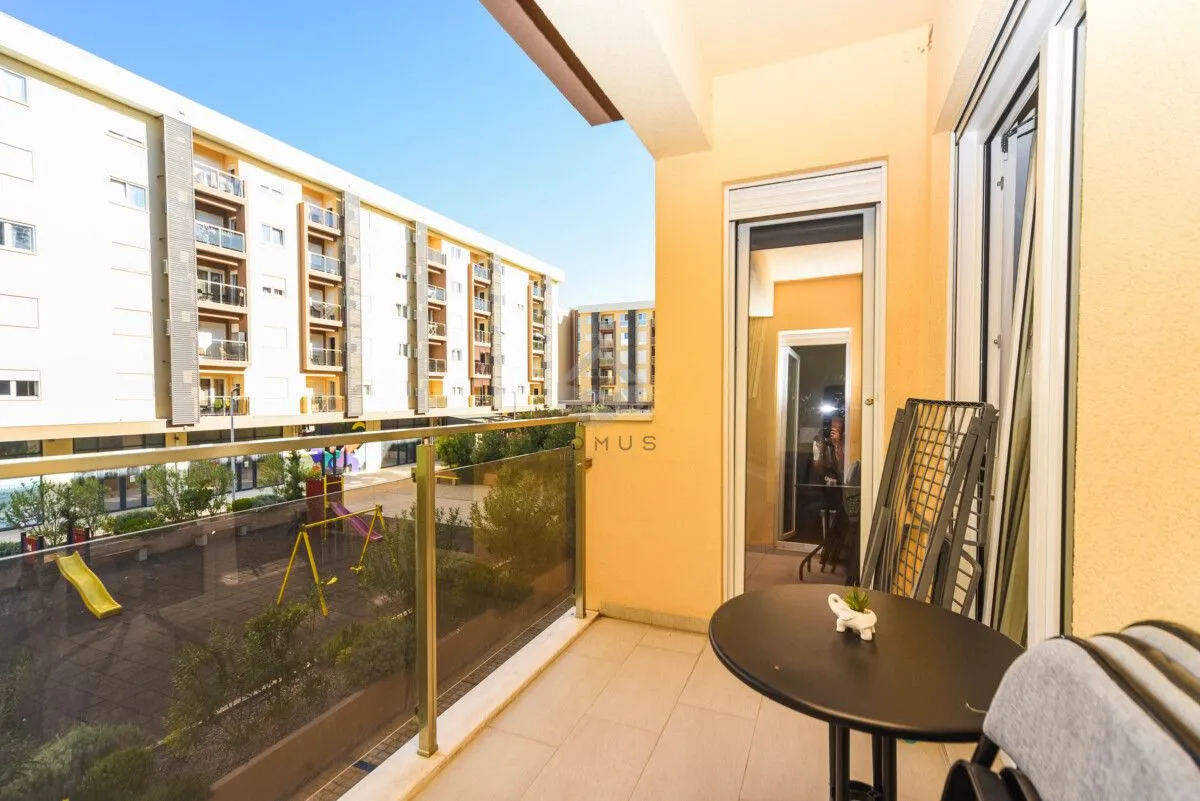 Namješten balkon sa stolom i pogledom na naselje i igralište.