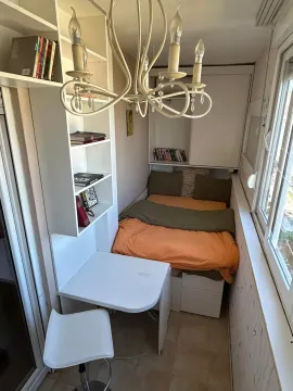 Small bedroom with a bed, desk, and bookshelves. - image 2