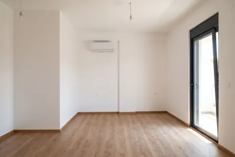 Prazna svijetla soba sa drvenim podom, bijelim zidovima i klima uređajem. - image 3