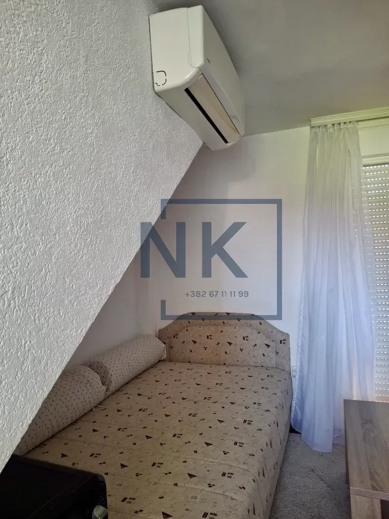 Small bedroom with a bed and an air conditioner.