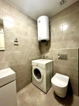 Manje kupatilo obloženo keramičkim pločicama sa wc šoljom, umivaonikom, veš mašinom i bojlerom. - image 6