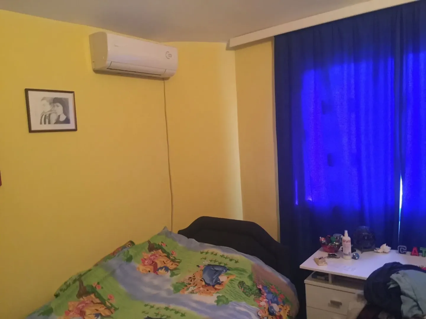 Bedroom with yellow walls, an air conditioner, and blue curtains.
