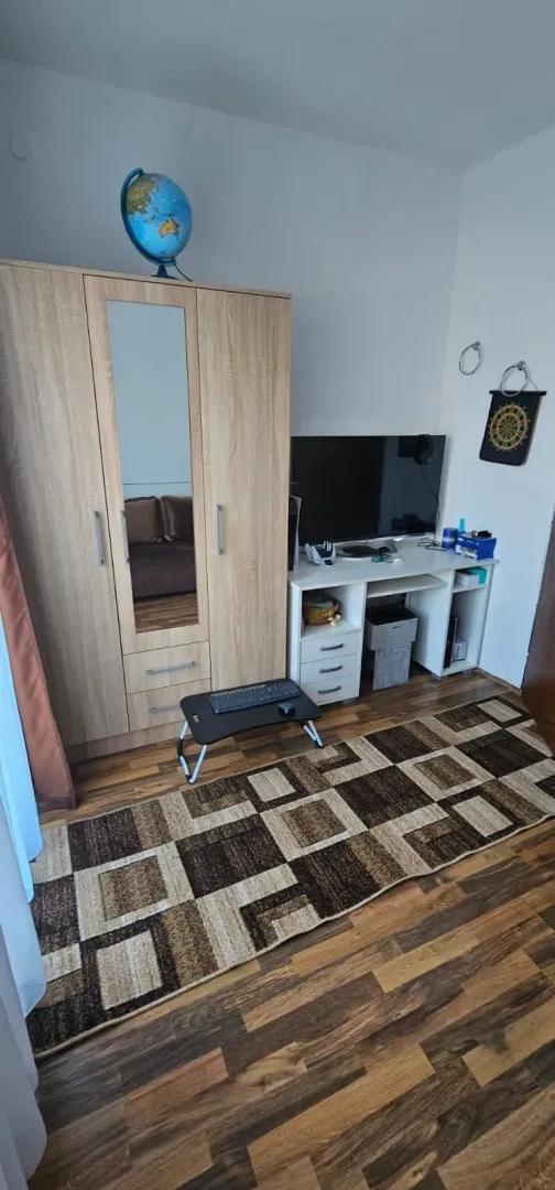 Namještena spavaća soba sa ormarom, radnim stolom i televizorom.
