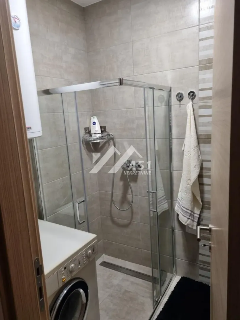 Manje kupatilo sa tuš kabinom i veš mašinom.