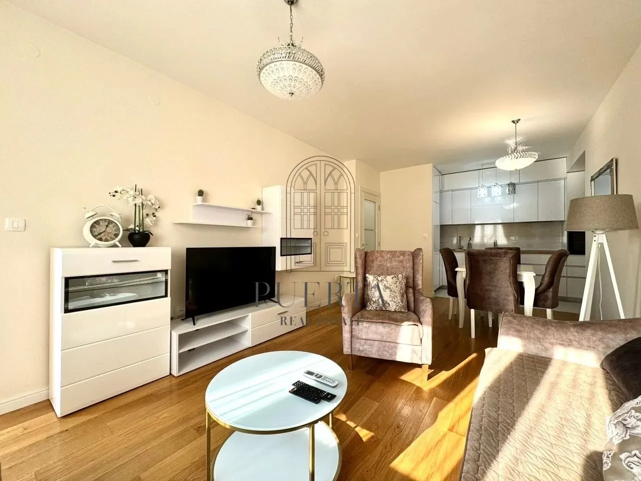 Living room with sofa, TV and dining area in the background.
