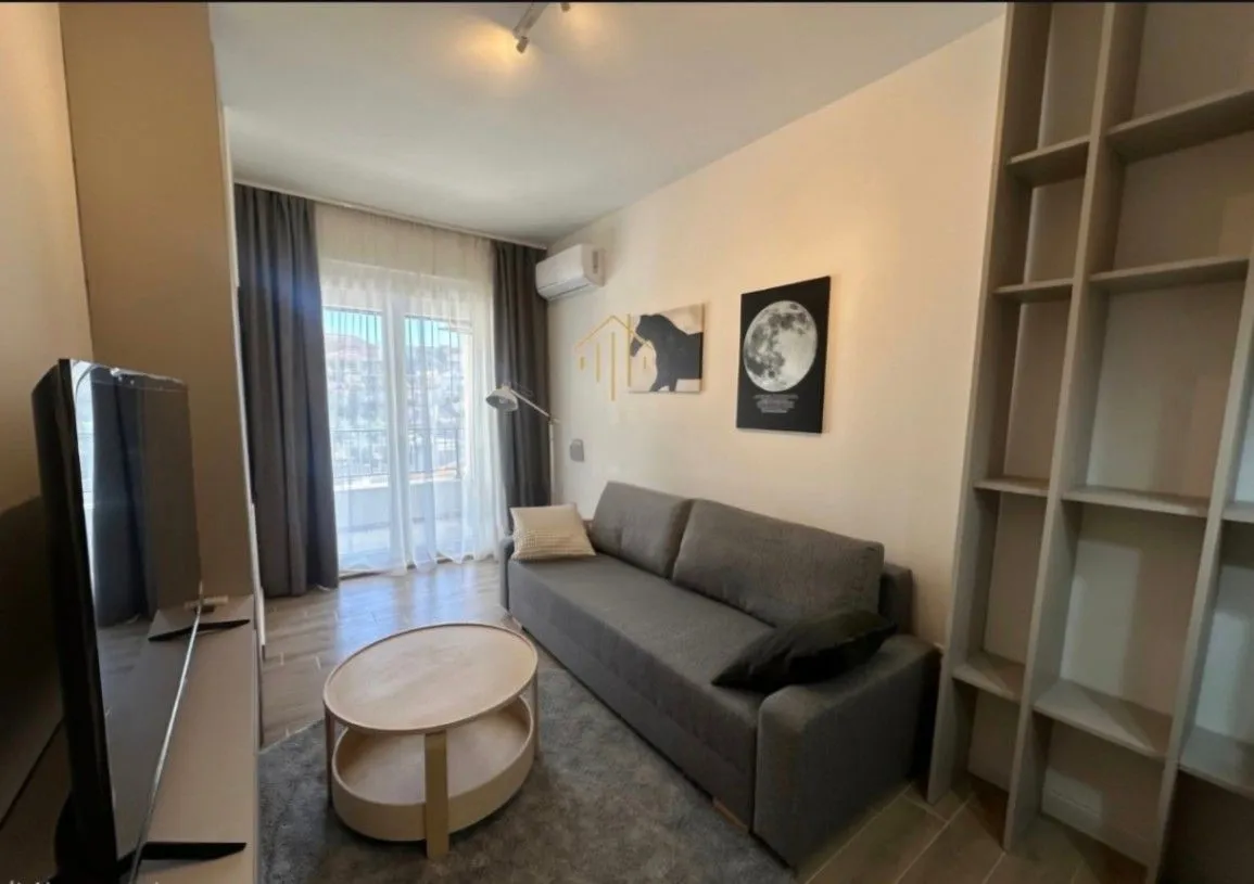 Living room with a grey sofa, coffee table, and shelving unit.