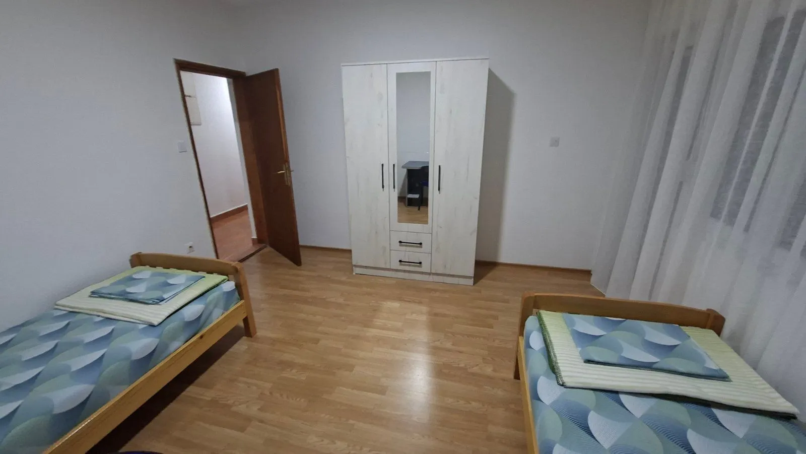 Spavaća soba sa dva kreveta i bijelim ormarom.
