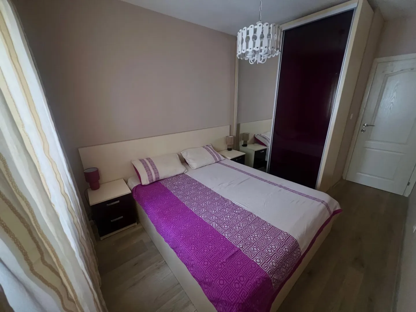 Bedroom with a double bed, bedside tables and a large wardrobe with a mirror.