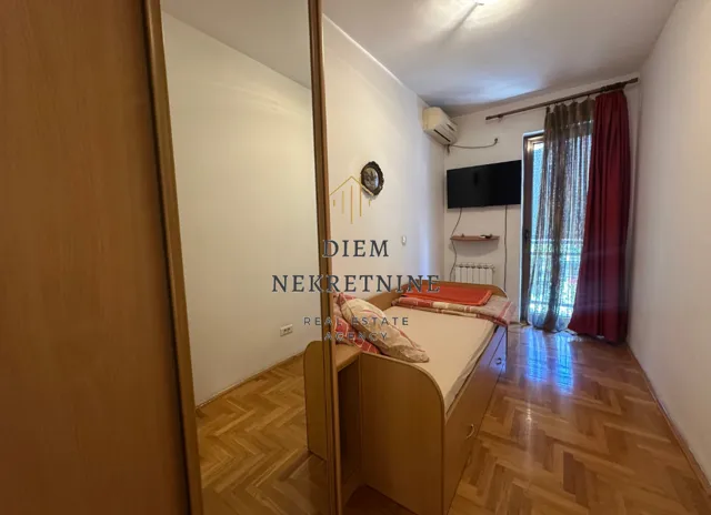 Smaller bedroom with a bed, wardrobe, and balcony access.