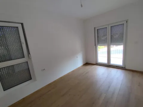 Empty room with white walls, laminate flooring, and windows with roller shutters. - image 8