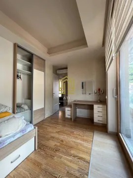 Furnished bedroom with a built-in wardrobe, desk, and large window. - image 7