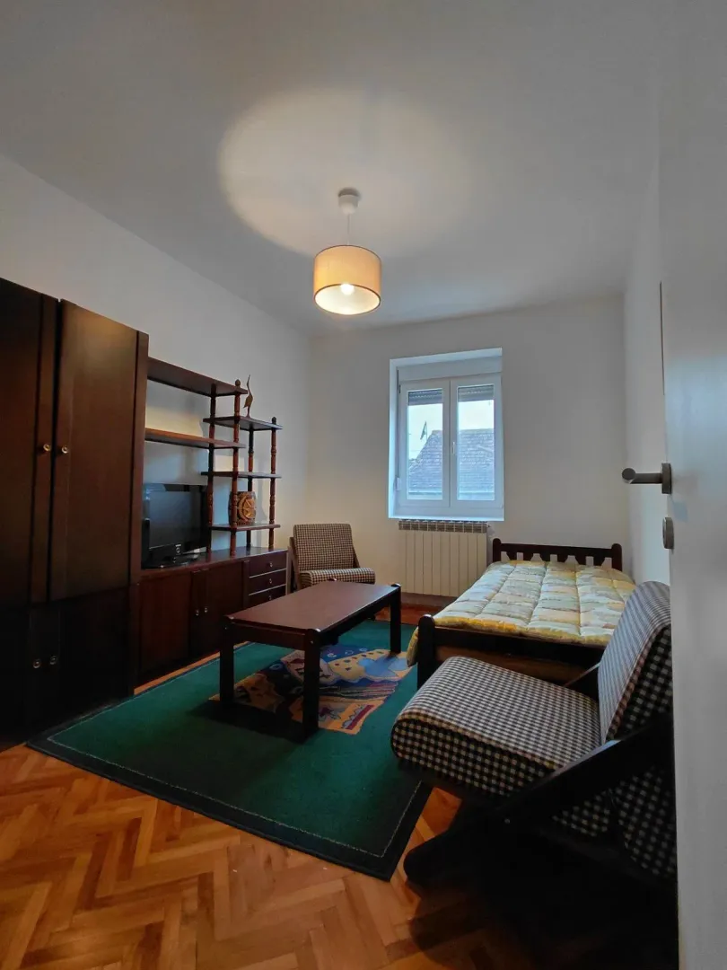 Furnished bedroom with a bed, wardrobe, and table.