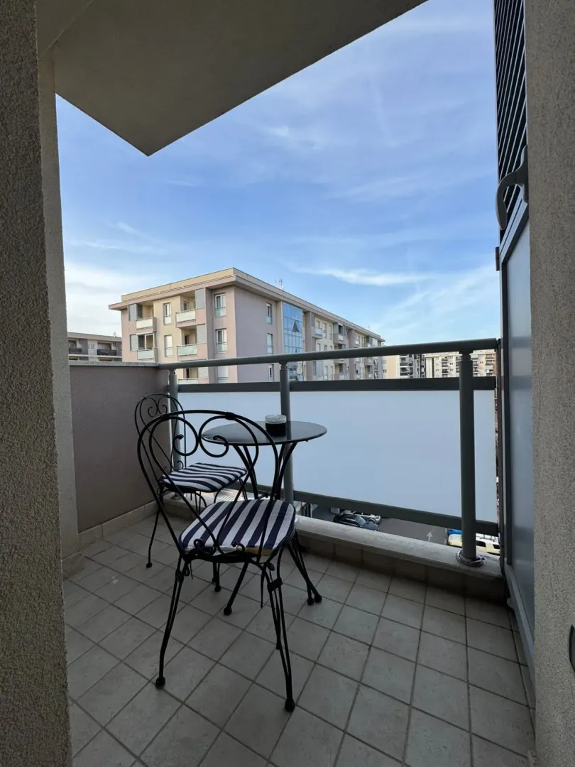 Namješten balkon sa garniturom za sjedenje i pogledom na okolne zgrade.
