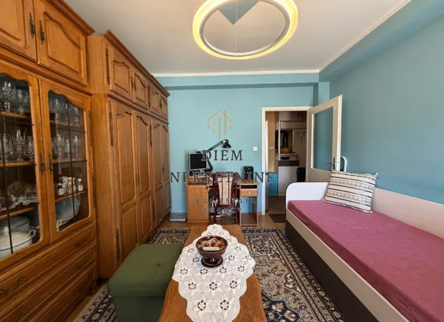Furnished bedroom with large wooden wardrobes, a bed, and a desk.