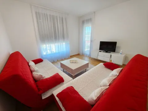 Living room with red sofas, a coffee table, and a TV. - image 2