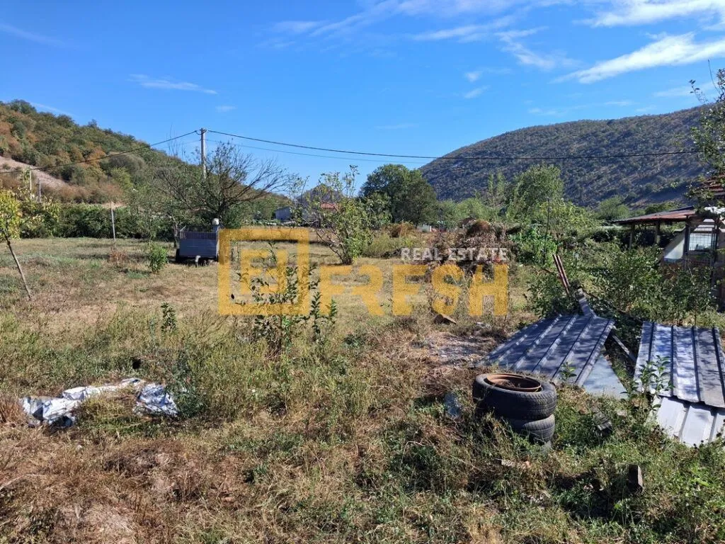Pogled na prostrano dvorište sa zelenilom i okolnim brdima.