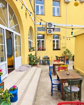 Spoljašnji deo restorana sa stolovima i šarenim stolicama ispred ulaza. - image 14