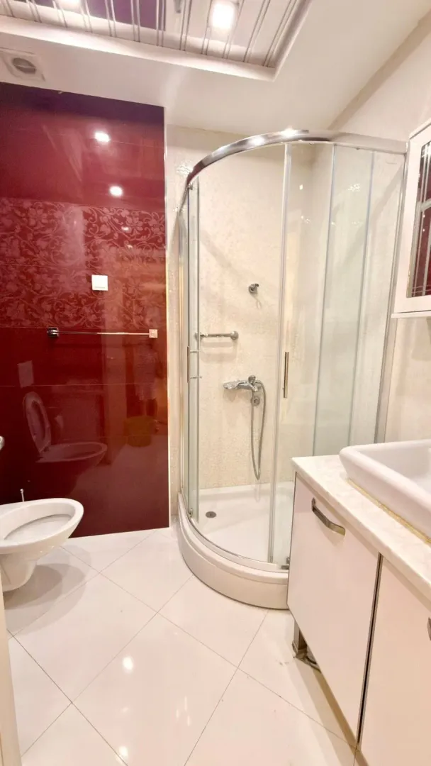 Bathroom with a shower cabin, washbasin, and toilet.