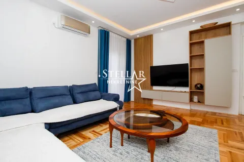 Living room with a blue sectional sofa, wooden coffee table, and TV unit. - image 3