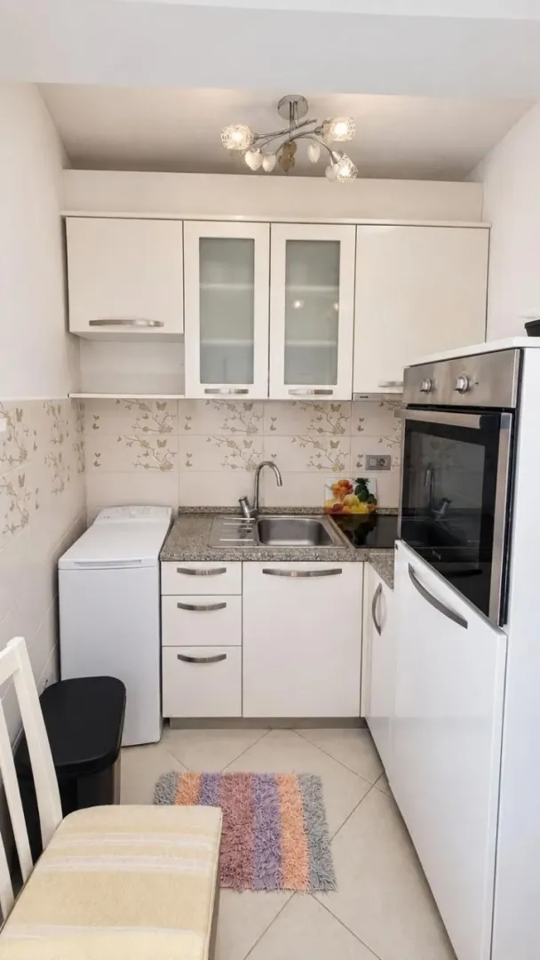 Manja bijela kuhinja sa ugrađenom rernom, sudoperom i mašinom za veš.