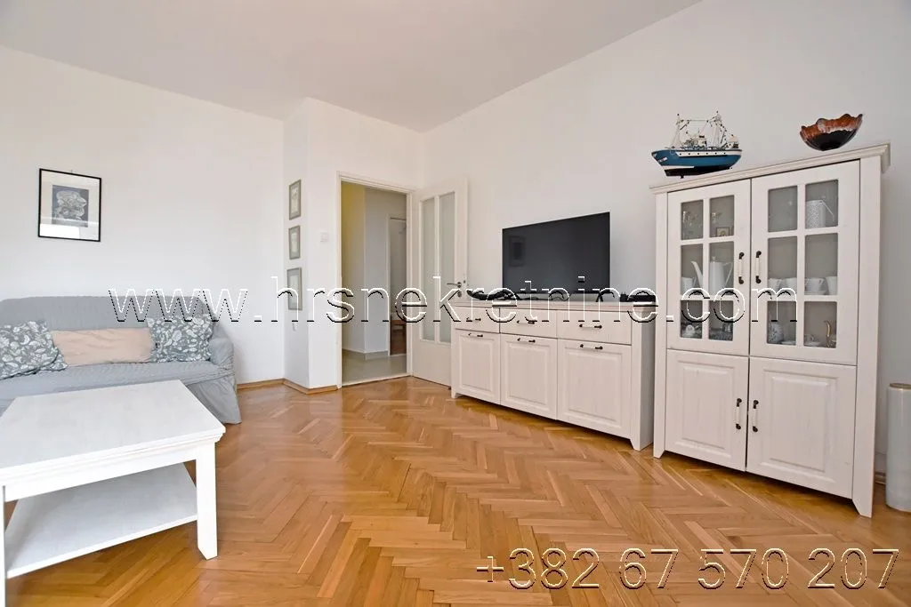 Living room with sofa, TV cabinet, and wooden flooring.