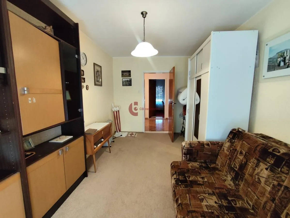 Small living room with a sofa, wooden cabinets, and carpeted floor.
