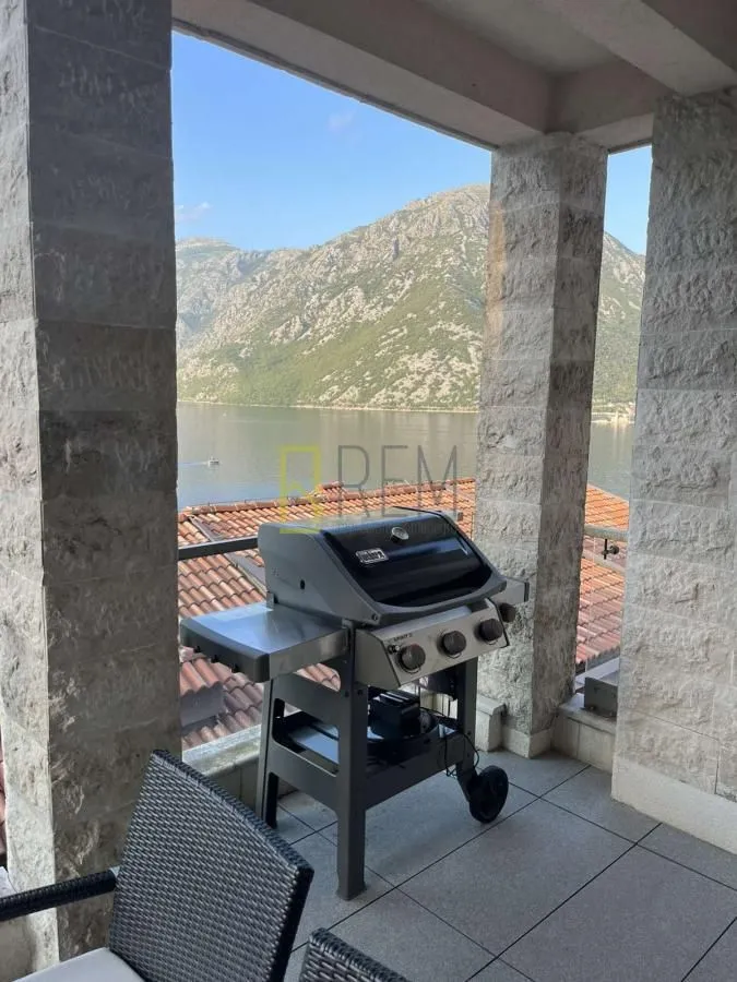 Natkrivena terasa sa roštiljem i pogledom na zaliv i planine.