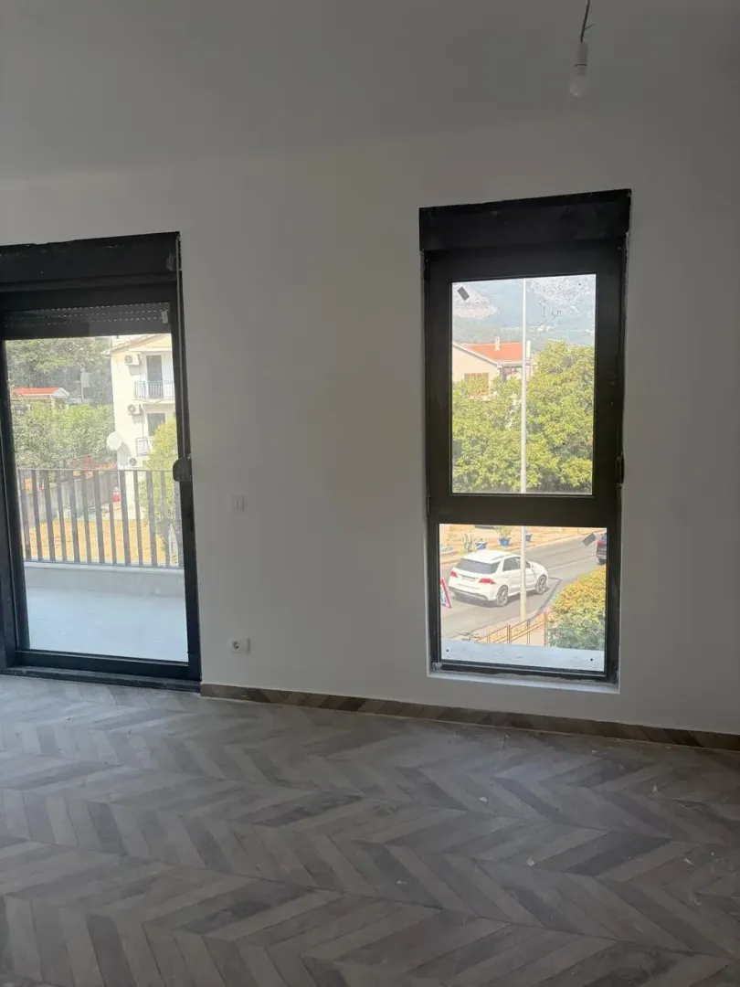 Prazna prostorija sa parketom i prozorima koji gledaju na ulicu.