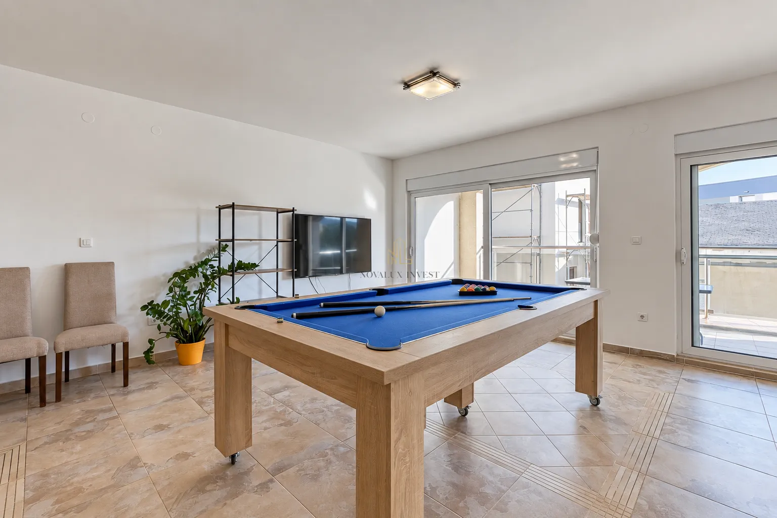 Spacious living room with a pool table and terrace access.