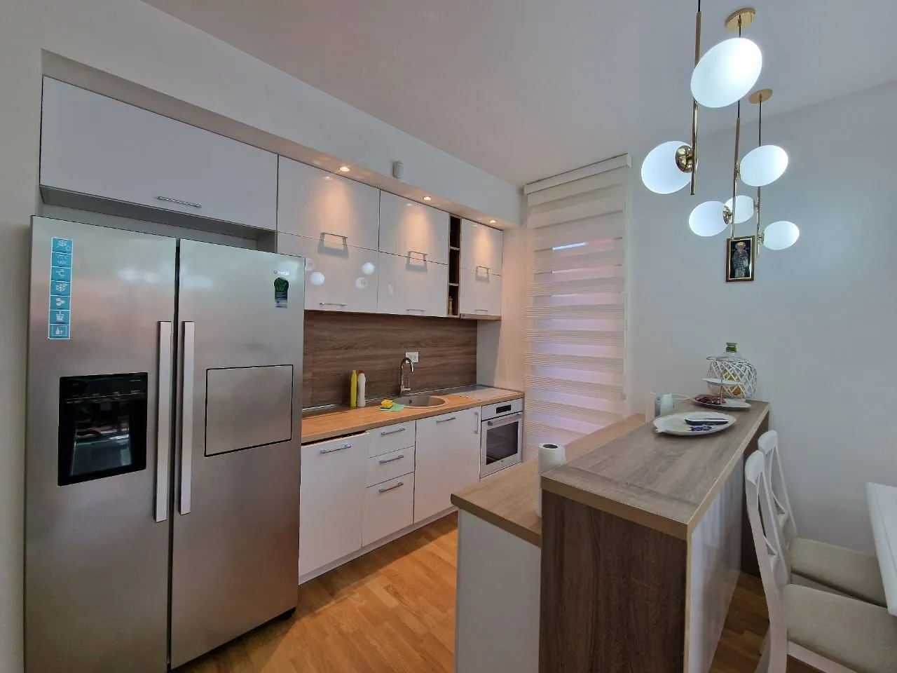 Modern kitchen with white units, a breakfast bar, and built-in appliances.