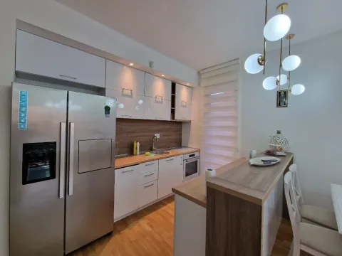 Modern kitchen with white units, a breakfast bar, and built-in appliances. - image 21