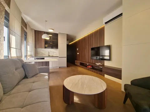 Living room with a sofa, TV, and a view of the kitchen in the background. - image 2