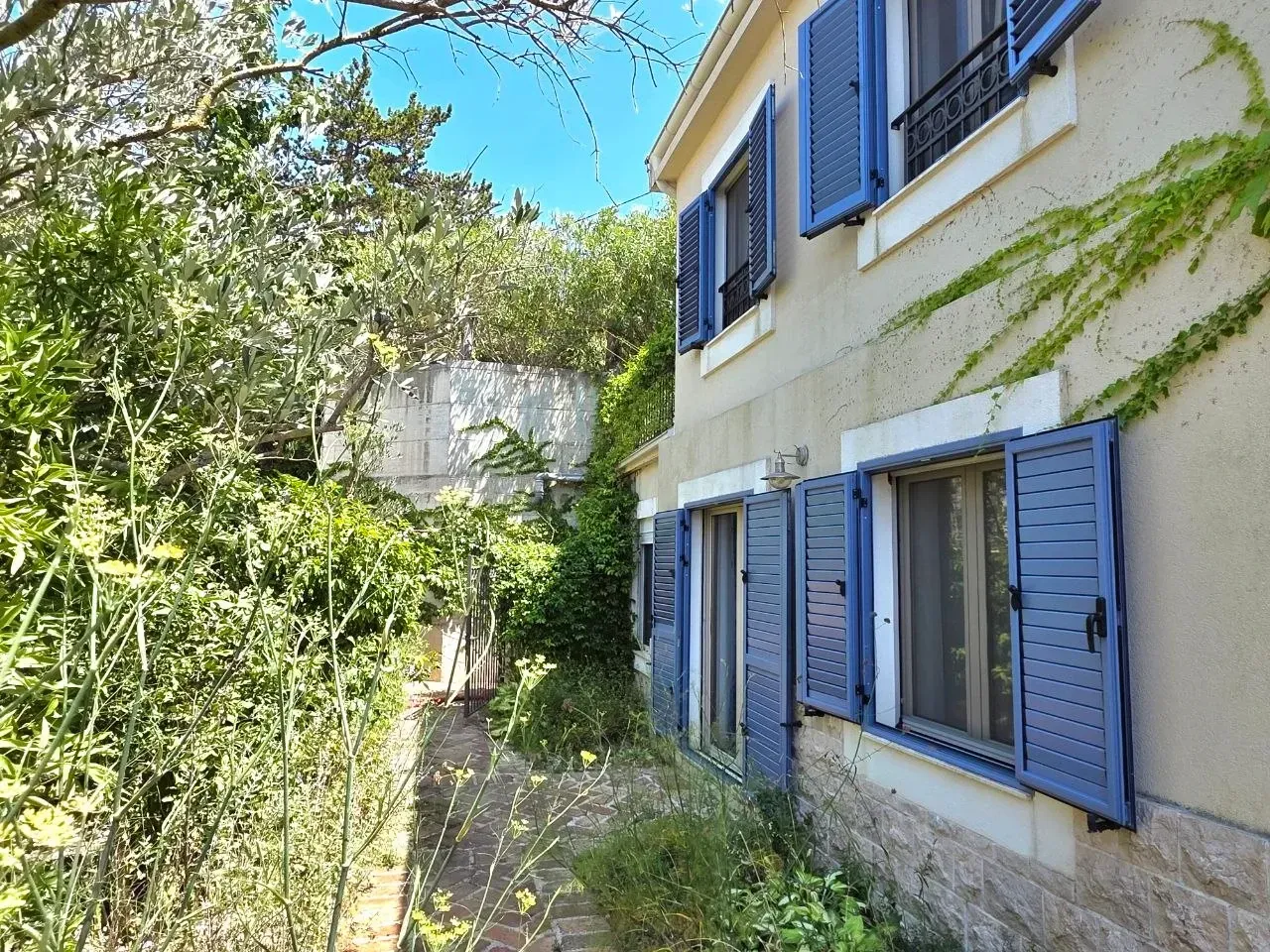 Pogled na spoljašnjost kuće sa dvorištem i zelenilom.