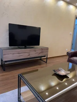 Dio dnevne sobe sa televizorom, modernom komodom i staklenim klub stolom. - image 16